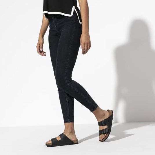 Person wearing black jeans and black sandals on a white background