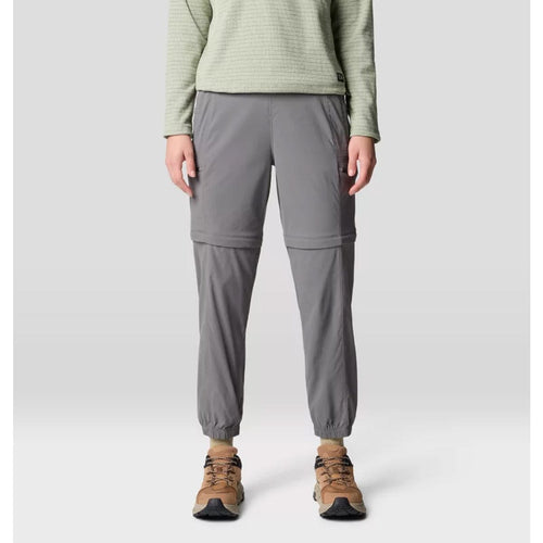A pair of gray Mountain Hardwear women's Dynama convertible utility joggers with a zipper at the lower half for detachable short wear, featuring a wide and low-profile stretch waistband, side entry hand pockets, and secure zip cargo thigh pockets.