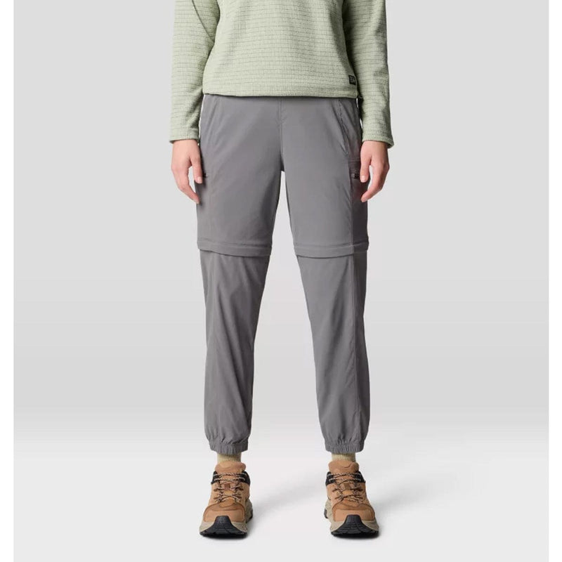 Load image into Gallery viewer, A pair of gray Mountain Hardwear women&#39;s Dynama convertible utility joggers with a zipper at the lower half for detachable short wear, featuring a wide and low-profile stretch waistband, side entry hand pockets, and secure zip cargo thigh pockets.
