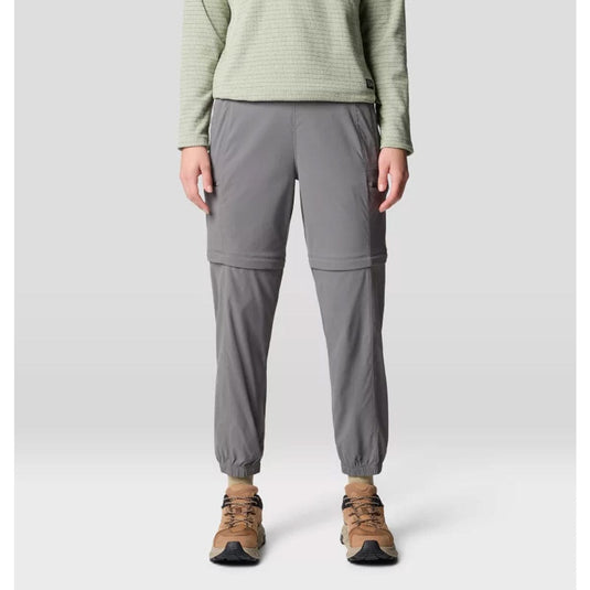 A pair of gray Mountain Hardwear women's Dynama convertible utility joggers with a zipper at the lower half for detachable short wear, featuring a wide and low-profile stretch waistband, side entry hand pockets, and secure zip cargo thigh pockets.