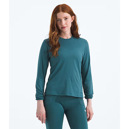 Woman wearing a teal long-sleeve top and leggings on a white background