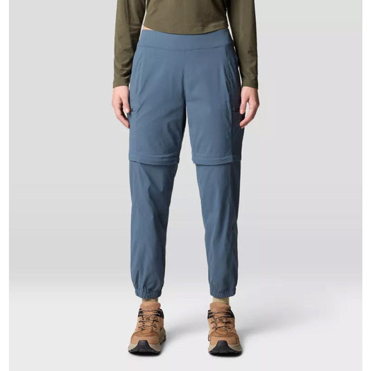 A pair of gray Mountain Hardwear women's Dynama convertible utility joggers with a zipper at the lower half for detachable short wear, featuring a wide and low-profile stretch waistband, side entry hand pockets, and secure zip cargo thigh pockets.