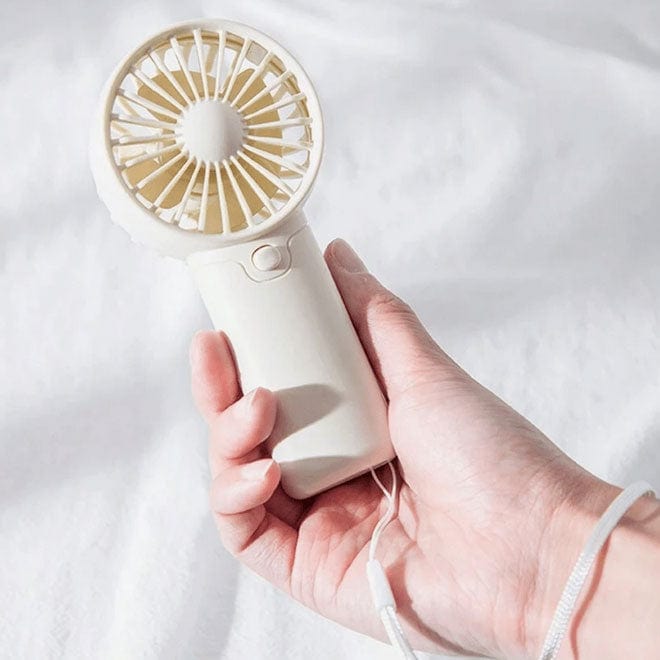 Load image into Gallery viewer, Hand holding a white handheld fan with gold accents on a light background